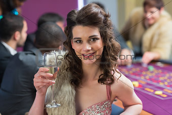 Woman smiling raising her glass at roulette table