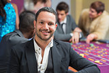 Smiling man sitting leaning on roulette table