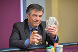 Man holding money smiling at roulette table