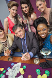 Man surrounded by beautiful women at roulette table