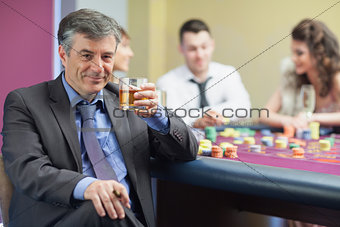 Man drinking whiskey at roulette table