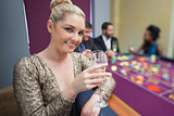 Blonde lifting champagne glass at roulette table