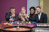 Four people toasting with champagne at roulette