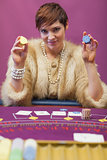 Woman holding up chips at poker game