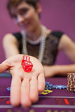 Woman sitting at table while holding dices