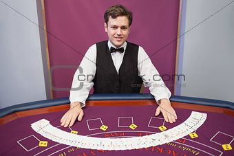 Smiling dealer with fanned out deck of cards
