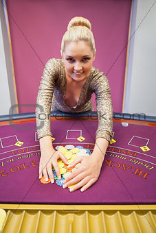 Smiling woman grabbing chips in a casino