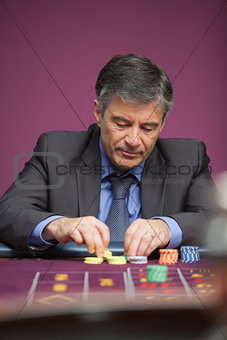 Man grabbing chips and playing roulette