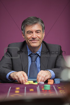 Smiling man playing roulette in a casino