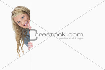 Blue-eyed woman hiding behind a poster