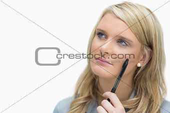 Woman looking up while holding a pen