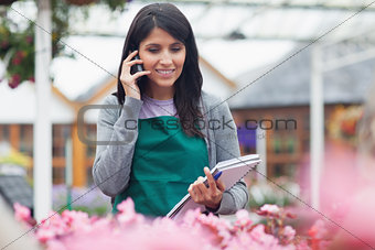 Garden center worker phoning while taking notes