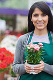 Garden center worker holding a potted flower and smiling
