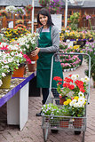 Woman filling the trolley with plants in the garden center