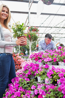 Woman holding a plant while man is looking through flowers