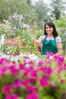 Woman having fun while watering plants with hose