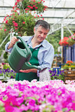 Smiling man watering flowers