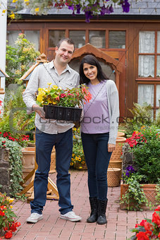 Smiling couple holding tray of plants