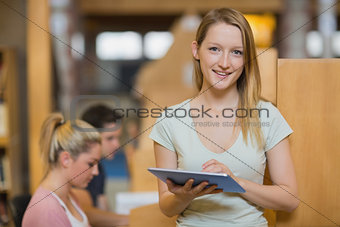 Woman standing holding a tablet computer while smiling