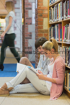 Boy and girl sitting on floor of library studying