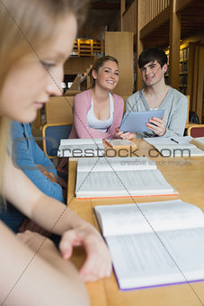 Happy students with tablet pc in library