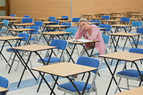 Student sitting at desk in empty exam hall