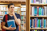 Student standing at the bookshelf thinking
