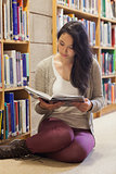 Woman sitting on library floor reading book