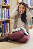 Stressed student sitting on library floor