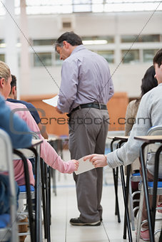 Students passing notes as teacher is talking to student
