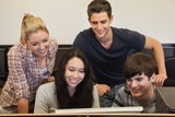 Students sitting standing looking at computer