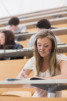 Woman sitting in lecture while writing notes