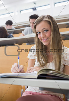 Woman sitting at the lecture hall making notes