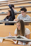 Student sitting at the lecture hall with hand up