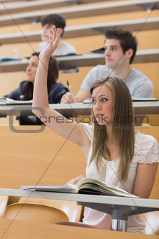 Woman sitting at the lecture hall with hand up
