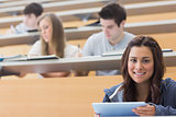 Smiling student taking notes with tablet pc