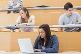 Students in a lecture with one using laptop