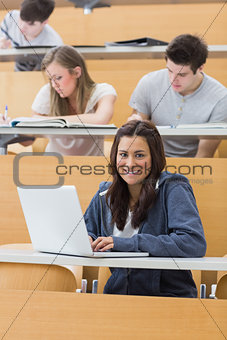 Smiling student in lecture with laptop