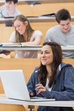 Girl sitting in lecture hall using laptop