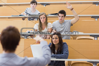 Students sitting at the lecture hall with man raising hand to ask question