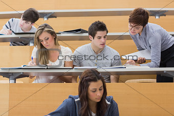 Students sitting at the lecture hall while teacher explaining