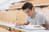Student sitting reading a book and taking notes