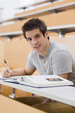 Student smiling while sitting and taking notes