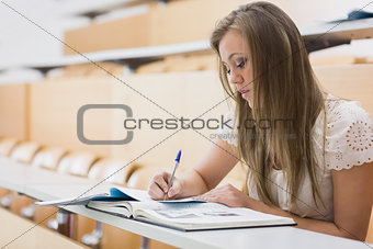 Concentrating woman sitting at the lecture hall writing