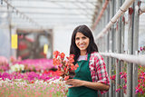 Woman holding a flower working in a greenhouse