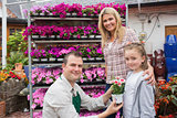 Employee presenting flower pot to little girl with mother