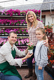 Employee giving flower pot to little girl with mother