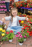 Little girl doing thumbs up sitting in garden centre