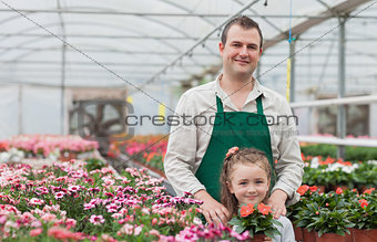 Little girl and gardener standing in greenhouse