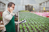Gardener calling and taking notes in greenhouse
